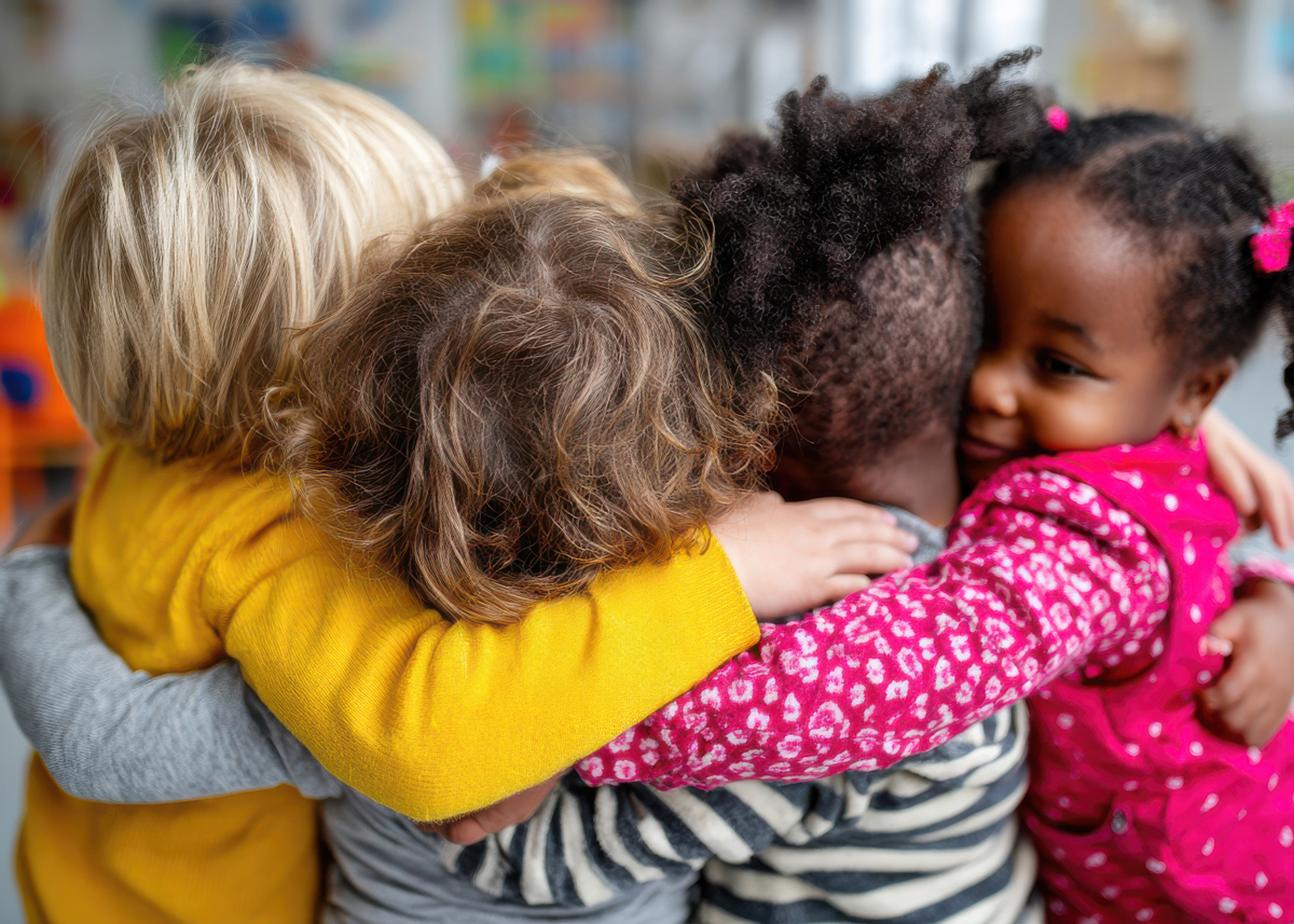 Preschool children of various ethnicities hugging in a circle at kindergarten, symbol of innocence and inclusion from early childhood