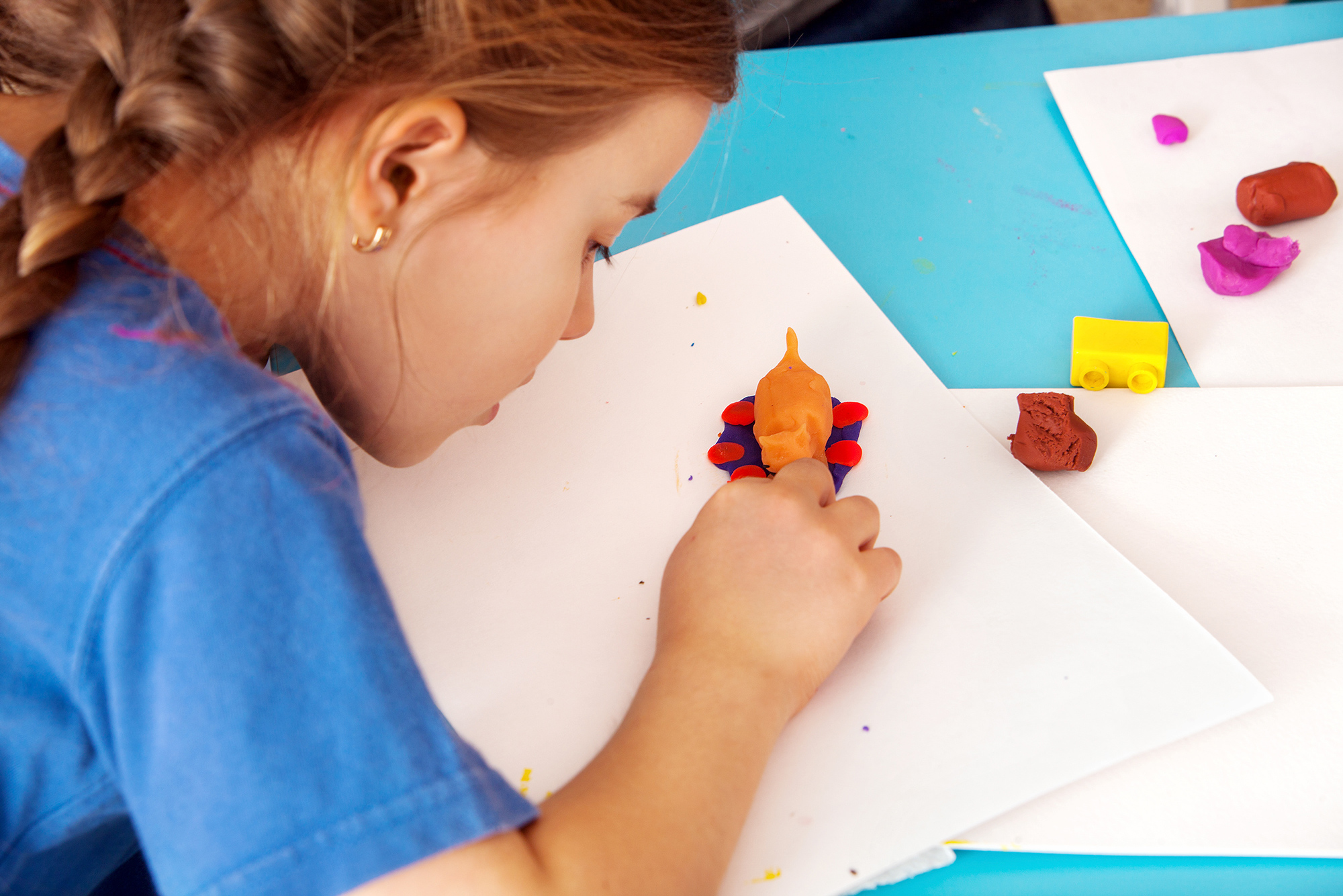 young girl child kneading modeling clay with hands in preschool