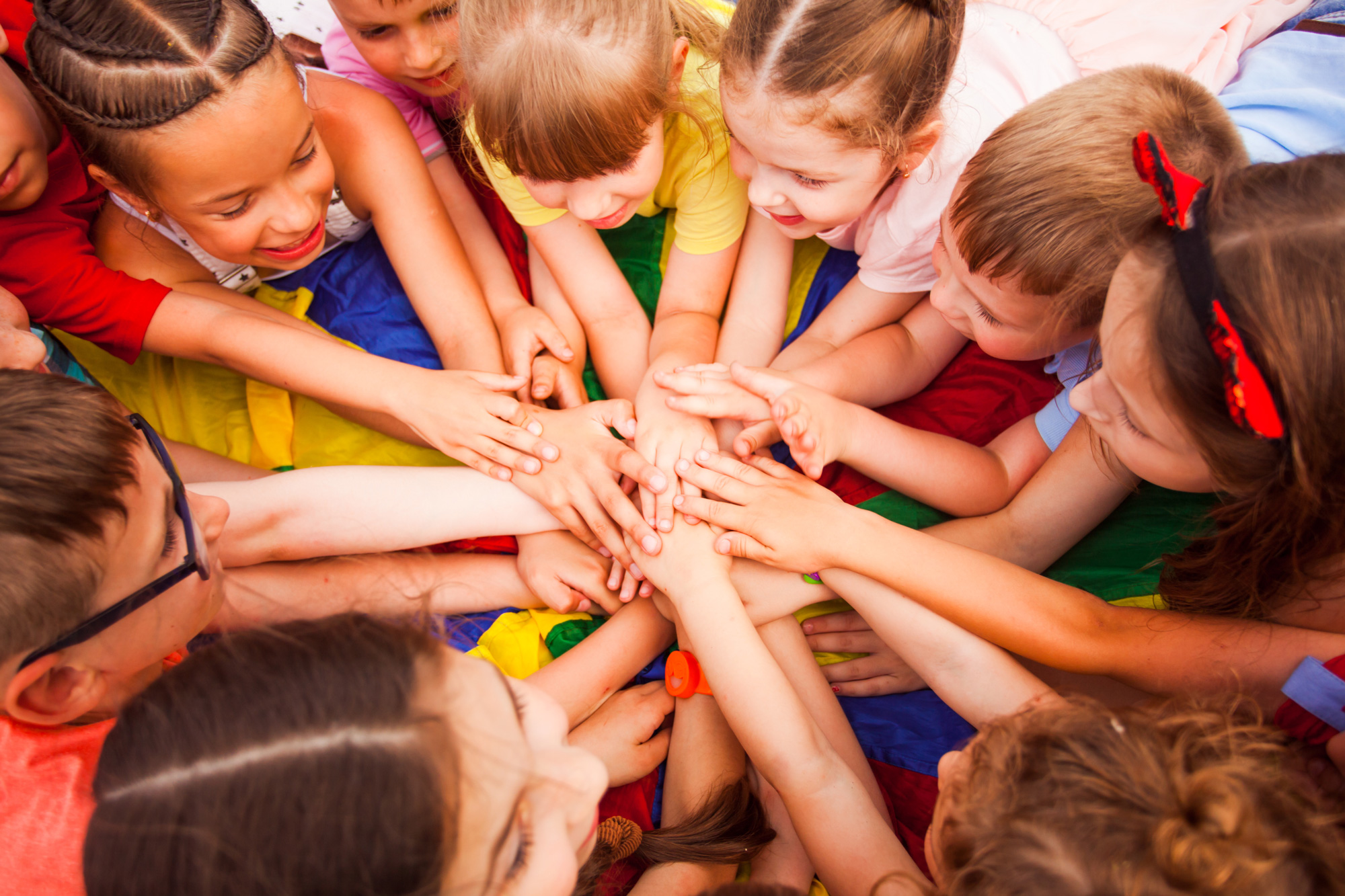 Children holding hands together, laying on a floor