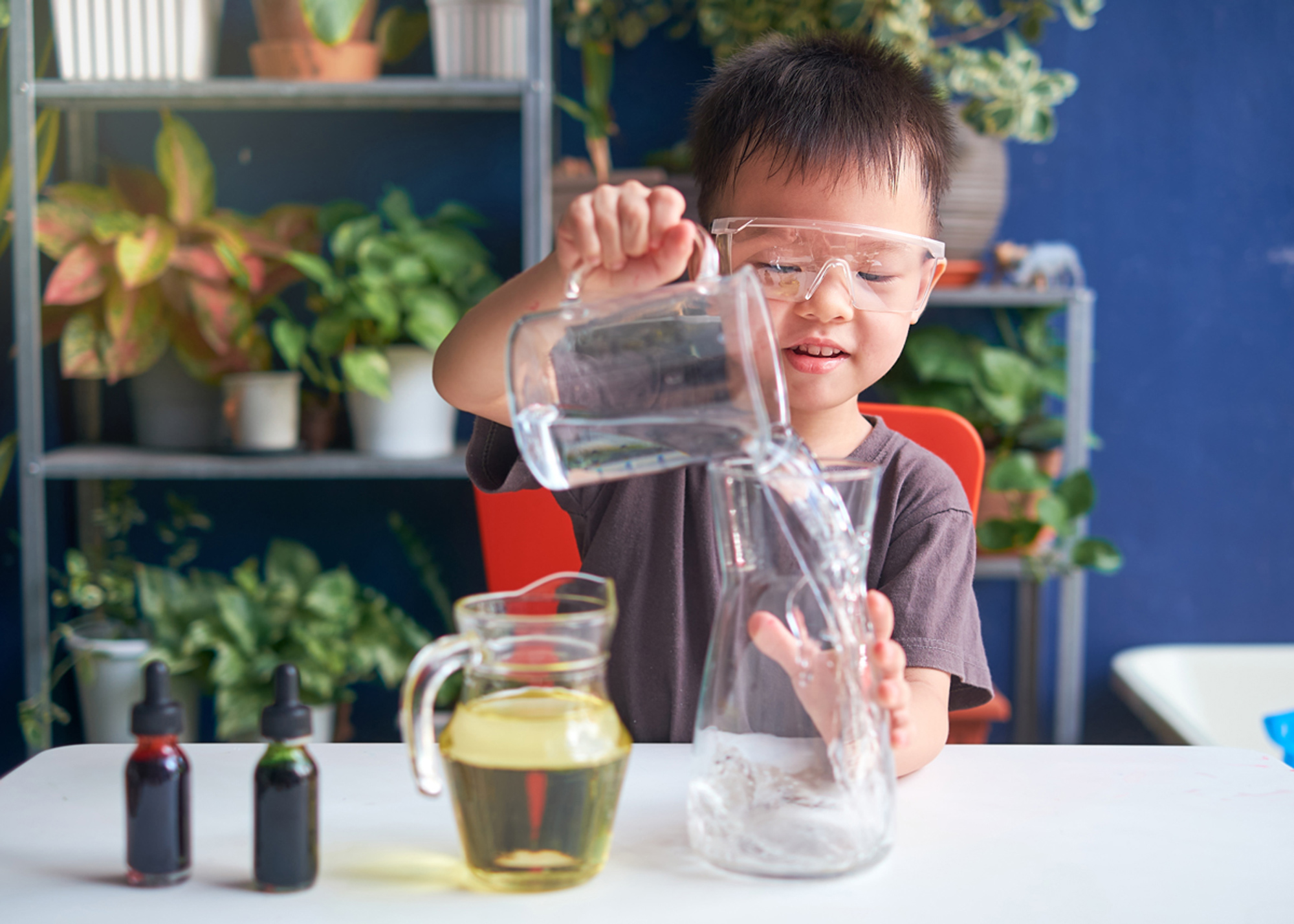 Toddler Asian school kid studying science, making DIY Lava Lamp Science Experiment with oil, water and food coloring.